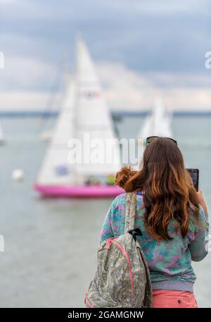 dame regardant la mer, dame regardant les bateaux à la semaine de cowes, femme spectateur à la régate de yachting, jeune femme se tenant à la mer, observant les yachts. Banque D'Images