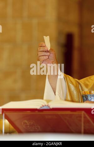 Rite de communion pendant la messe dans une église catholique. Le prêtre montre l'hôte aux fidèles Banque D'Images