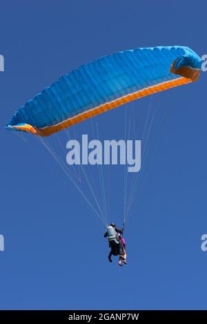 Vol en parapente bleu et orange en tandem, premier vol Banque D'Images