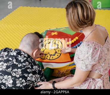 Les enfants ayant un handicap se font une activité sensorielle avec des jouets, des balles, des petits objets, un garçon souffrant de paralysie cérébrale jouant à un jeu apaisant, s'entraîner à de fines aptitudes motrices Banque D'Images