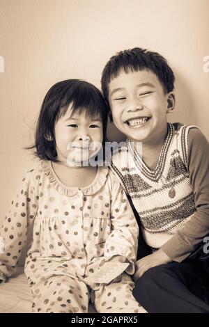 Petits enfants asiatiques (thaïlandais) heureux, frère et sœur souriant, aimant et liant de concept frère et sœur. Fond crème. Style d'image vintage Banque D'Images