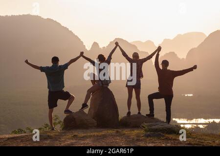 Concept de togethness avec quatre silhouettes de jeunes amis debout contre le lever du soleil et les montagnes Banque D'Images