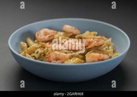 Pâtes Penne aux crevettes et pesto dans un bol bleu, peu profondes Banque D'Images