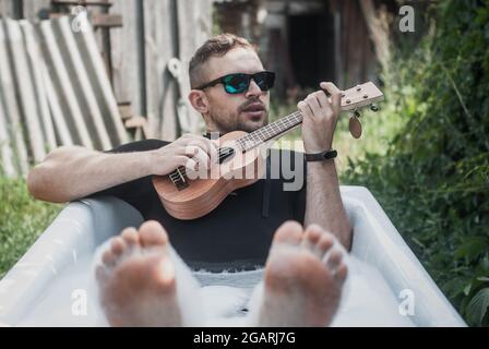 un homme dans le pays joue le ukulele Banque D'Images