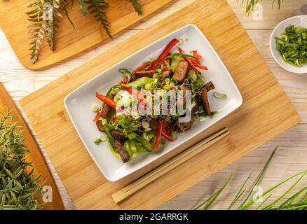 Assiette de salade asiatique avec cubes de bœuf décorés de pousses Banque D'Images