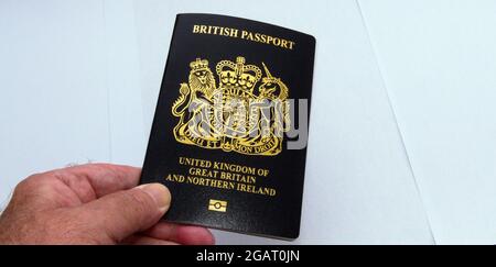 La main de l'homme senior tient un nouveau passeport britannique bleu foncé sur un fond blanc Banque D'Images