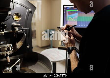 Un jeune travailleur spécialisé torréfaction du café dans un hangar Banque D'Images