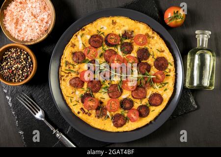 Œufs brouillés avec saucisses, tomates, poivre et ciboulette sur une assiette. Repas copieux. Régime de céto. Omelette aux œufs avec légumes. Banque D'Images