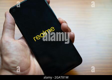 Main d'une personne tenant le nouveau smartphone Realme 8 pendant la mise sous tension. Présentation du nouveau téléphone mobile android. Banque D'Images