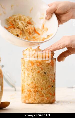 Femme mettant la choucroute savoureuse dans un pot en verre sur une table dans la cuisine, gros plan Banque D'Images