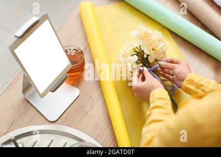 Fleuriste féminin avec de belles fleurs de narcisse dans l'atelier Banque D'Images