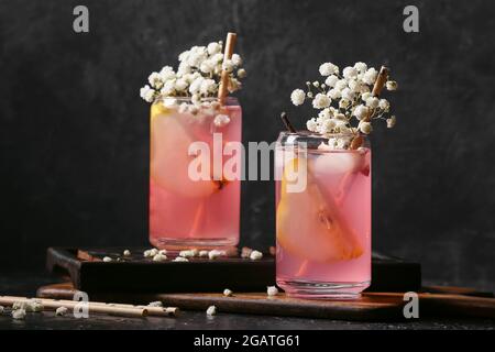 Verres avec délicieux cocktail et belles fleurs de gitsophila sur fond sombre Banque D'Images