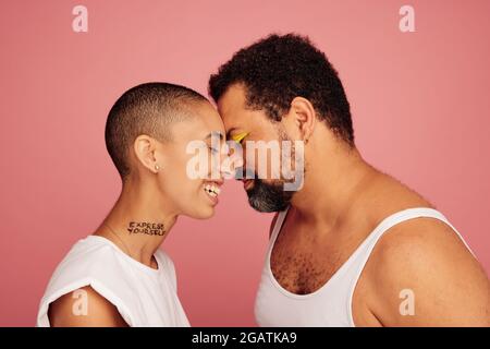 Des amis qui se tiennent ensemble agaisnst partialité. Homme et femme touchant leur tête sur fond rose. Banque D'Images