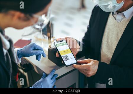 voyageur montrant son passeport de vaccination numérique au téléphone au préposé de la compagnie aérienne au comptoir d'enregistrement. Enregistrement des passagers avec e-passeport immunité à airpor Banque D'Images