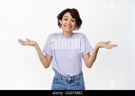 Rien à dire désolé. Souriante mignonne et coy brune femme écartée les mains vides sur les côtés, haussant les épaules sily, agissant comme si ne sais rien Banque D'Images