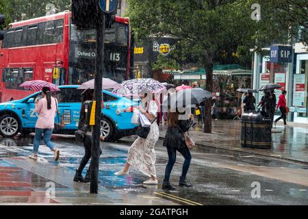 Pic shows: Le temps humide a frappé les acheteurs à Oxford Street le samedi après-midi alors que le juillet pluvieux a continué au tout dernier jour du mois 31.7.21 Banque D'Images