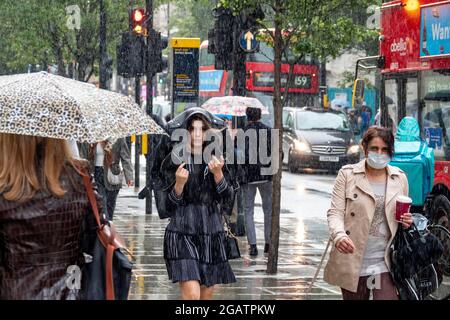 Pic shows: Le temps humide a frappé les acheteurs à Oxford Street le samedi après-midi alors que le juillet pluvieux a continué au tout dernier jour du mois 31.7.21 Banque D'Images