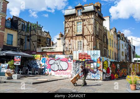 Graffiti coloré et bâtiments à pans de bois à Rennes, Bretagne, France. Un homme avec un tramway qui passe. Banque D'Images