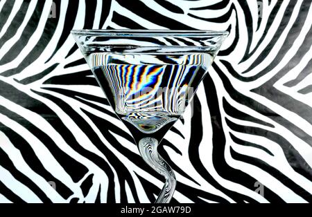 Réfraction de la lumière dans un verre d'eau qui inverse et déforme le motif d'impression Zebra derrière Banque D'Images