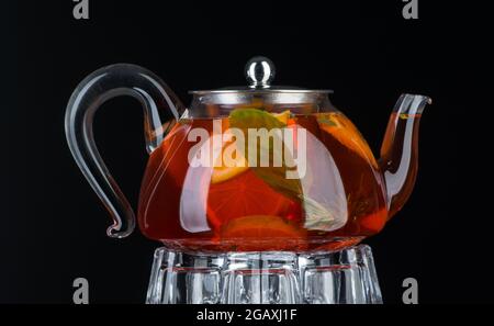 Thé à la menthe et au citron dans une théière transparente sur fond noir. Isolé Banque D'Images