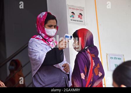 Dhaka, Bangladesh. 1er août 2021. Le personnel de sécurité vérifie la température corporelle des travailleurs de l'habillement avant d'entrer dans une usine de vêtements après la réouverture des usines de vêtements pendant le confinement de Covid-19 à Dhaka, au Bangladesh, le 1er août 2021. Credit: Mamunur Rashid/Alamy Live News Banque D'Images