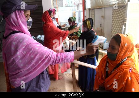 Dhaka, Bangladesh. 1er août 2021. Le personnel de sécurité vérifie la température corporelle des travailleurs de l'habillement avant d'entrer dans une usine de vêtements après la réouverture des usines de vêtements pendant le confinement de Covid-19 à Dhaka, au Bangladesh, le 1er août 2021. Credit: Mamunur Rashid/Alamy Live News Banque D'Images