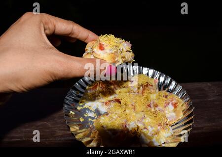 Une femme mangeant un savoureux aliment indien, le Bhelpuri populaire en-cas indien Banque D'Images