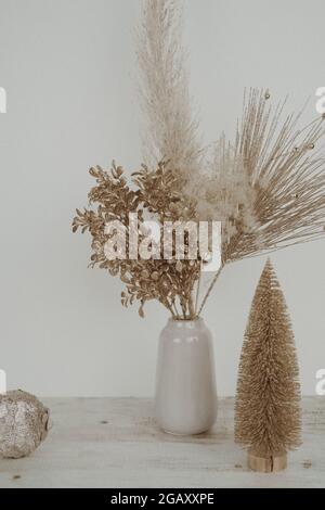 Vase avec l'herbe de pampas séchée sur un fond neutre avec arbre de Noël et boule près du mur. Herbe de pampas sèche, roseau dans un vase élégant. Photo de haute qualité Banque D'Images