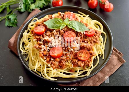 Spaghetti savoureux avec viande hachée, tomates cerises et parmesan sur l'assiette, vue rapprochée Banque D'Images
