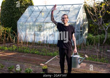 Woodbridge Suffolk Royaume-Uni Mai 08 2020: Un jeune homme tatoué hipster travaillant fièrement dans son jardin potager cultivant une gamme de légumes biologiques Banque D'Images