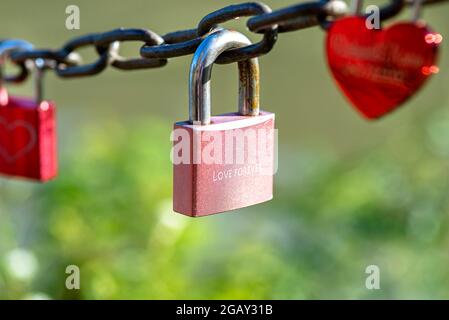 Un cadenas rose accroché à une chaîne gravée des mots amour pour toujours. Banque D'Images