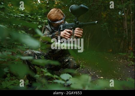 Guerrier de paintball avec des pousses de canon des buissons Banque D'Images