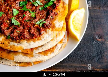 Gros plan vue de Lahmacun turc servi avec des lisières de citron : pains plats turcs recouverts de viande hachée épicée et garni de feuilles de menthe hachées Banque D'Images