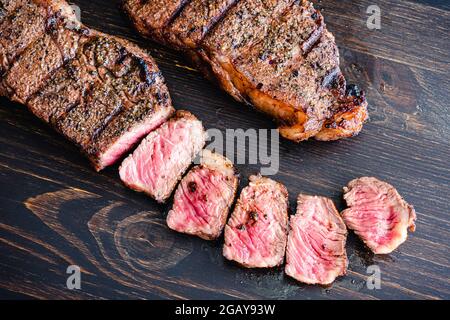Steak de New York grillé avec café : biftecks de New York grillés sur fond de bois sombre Banque D'Images