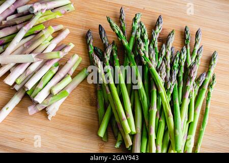 Épis d'asperges taillés sur une planche à découper en bambou : épis d'asperges crus sur une planche à découper en bois Banque D'Images