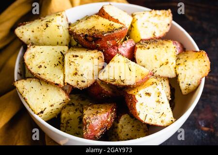 Pommes de terre rouges rôties dans un saladier : pommes de terre rouges rôties enrobées d'huile d'olive, d'épices et d'ail Banque D'Images