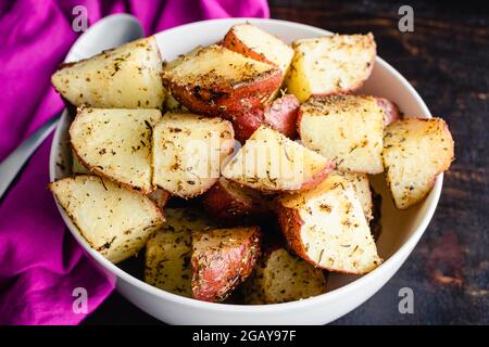 Pommes de terre rouges rôties dans un saladier : pommes de terre rouges rôties enrobées d'huile d'olive, d'épices et d'ail Banque D'Images