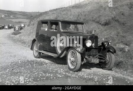 Années 1930, historique, à l'extérieur sur une piste de gravier dans une zone touristique de campagne, une famille assise dans un élégant quatre portes, voiture à roues en fil de l'époque, peut-être un Britannique fait Austin. Banque D'Images