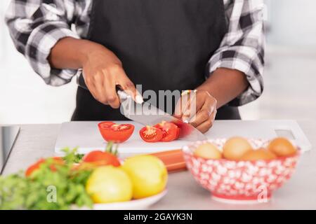 Afro-américaine femme émincée de tomates sur une planche à découper Banque D'Images