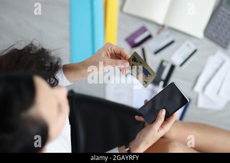 Femme tient dans la main carte de crédit en plastique et smartphone Banque D'Images