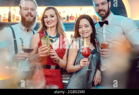 Jeune couple posant avec des verres à cocktail au bar Banque D'Images