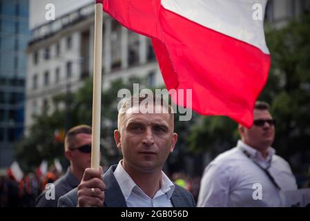 Varsovie, Pologne. 1er août 2021. Robert Bakiewicz, dirigeant du camp radical national (RNO), est vu arborer un drapeau polonais pendant le mois de mars.des milliers de personnes ont participé à une marche organisée par le camp radical national (RNO) et d'autres organisations nationalistes pour commémorer le 77e anniversaire du soulèvement de Varsovie (Powstanie Warszawskie). Crédit : SOPA Images Limited/Alamy Live News Banque D'Images