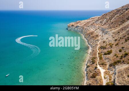 Bateaux à moteur quittant le sentier dans la baie de Pissouri, Chypre avec des falaises en forme de tortue géante et de mer Méditerranée sur fond, paysage marin aérien Banque D'Images