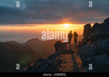 Un jeune couple heureux regardant le lever du soleil depuis le pic de Pico do Arieiro à Madère. Silhouette de couple sur les montagnes Banque D'Images