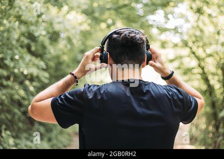 Jeune homme à l'écoute de la musique dans la nature. Vue arrière Banque D'Images