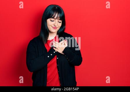 Jeune femme hispanique portant des vêtements décontractés souriant avec les mains sur la poitrine avec les yeux fermés et geste reconnaissant sur le visage. Concept de santé. Banque D'Images