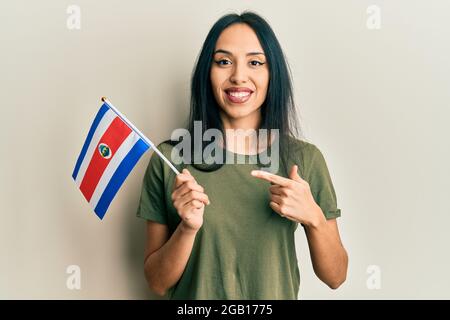 Jeune fille hispanique portant le drapeau du costa rica souriant heureux pointant avec la main et le doigt Banque D'Images