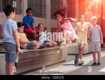 Jeu de saut de petite fille péruvienne par le groupe de caoutchouc avec des amis européens Banque D'Images