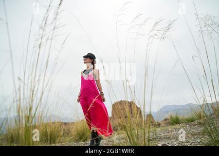 femme asiatique en robe rouge marchant dans un site historique desolate Banque D'Images