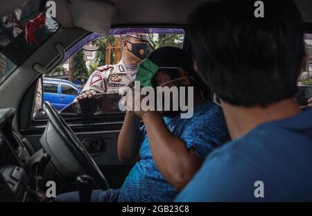 Makassar, Sulawesi du Sud, Indonésie. 2 août 2021. Un policier demande à un conducteur de porter un masque correctement lors d'un raid sur un protocole de santé à la frontière de la ville de Makassar et de Gowa Regency, en Indonésie. Un par un, les conducteurs qui ne portaient pas de masques ont été arrêtés et invités à porter des masques. L'inspection a été effectuée dans le cadre d'une série de mesures de restriction des activités communautaires de niveau 4 (PPKM) dans la ville de Makassar afin de supprimer la propagation de Covid-19 qui continue d'augmenter. (Image de crédit : © Herwin Bahar/ZUMA Press Wire) Banque D'Images